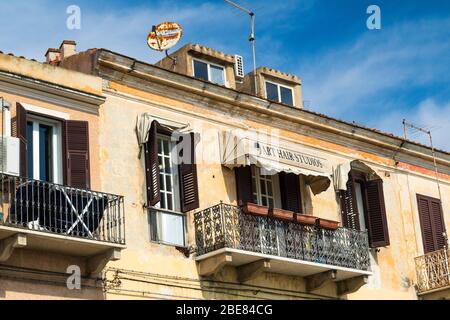 Balkone und Fensterläden: Detaillierte Außenansicht eines oberen Friseursalon mit Jalousien Fensterläden auf einem Gebäude in der Hauptstraße von La Maddalena Stockfoto