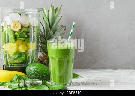 Mixer mit frischen Zutaten für eine gesunde Entgiftung Smoothie mit einem Glas grün vorbereitet Getränk mit einem Stroh. Veganes Kochkonzept Stockfoto
