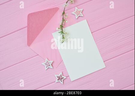 Zweig der weißen Kirschblüten auf rosa Holzhintergrund mit Blatt Mockup Papier, Sterne und Umschlag mit Platz für Ihren Text. Für Grußkarte Stockfoto