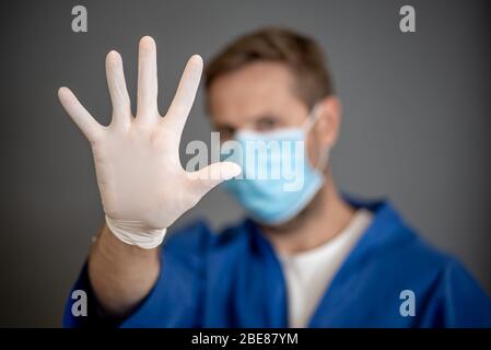 COVID-19 Ausbruch. Helfen Sie, die Ausbreitung des Virus zu stoppen. Arzt oder Krankenschwester mit chirurgischer Gesichtsmaske und Handschuhen PSA mit den Händen in STOP-Geste. Bleib s Stockfoto