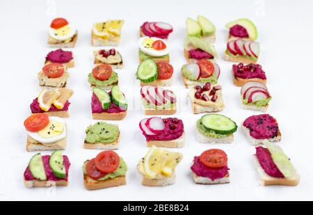 Set verschiedene Bruschetta Sandwiches mit Rübenhummus, Guacamole, verschiedene Gemüse. Vegetarisches Helsifood-Konzept. Sommernack. Food patern auf whit Stockfoto