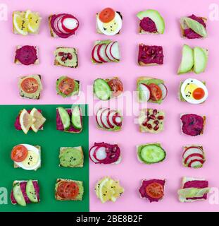 Set verschiedene Bruschetta Sandwiches mit Rübenhummus, Guacamole, verschiedene Gemüse. Vegetarisches Helsifood-Konzept. Sommernack. Food patern auf rosa Stockfoto