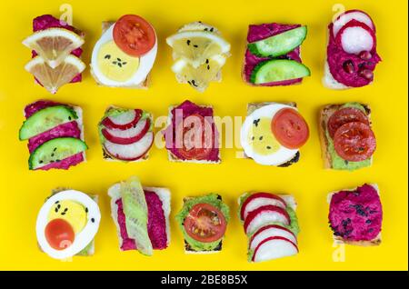 Set verschiedene Bruschetta Sandwiches mit Rübenhummus, Guacamole, verschiedene Gemüse. Vegetarisches Helsifood-Konzept. Sommernack. Food patern auf schreien Stockfoto