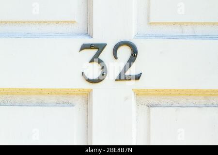 Haus Nummer 32 auf einer weißen Holztür Stockfoto