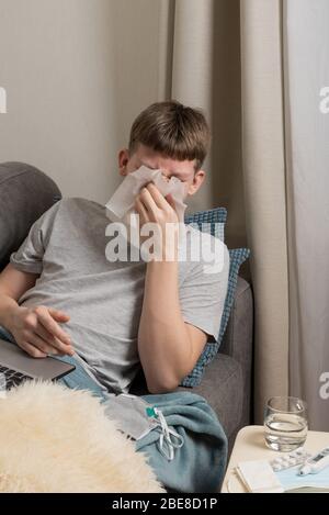 Kranke Teenager versucht, online zu studieren und niest in Papiertuch. Selbstisolierung. Quarantäne. ferngespräche elearning. Prävention von Coronavirus. Stockfoto