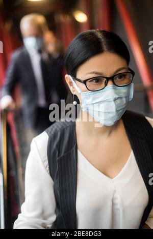 asiatische Geschäftsfrau in formelle Kleidung mit medizinischen Maske wegschauen Stockfoto