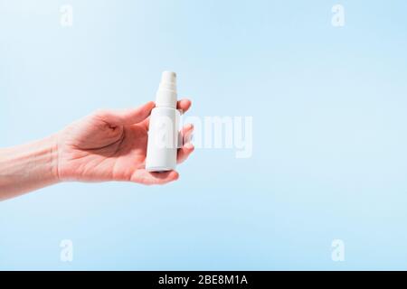 Plastikflasche mit Desinfektionsmittel in Spray in weiblicher Hand über blauem Hintergrund. Kopierbereich Stockfoto