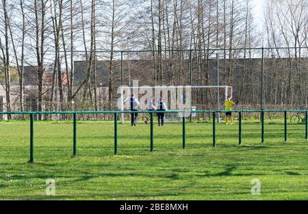 Belgien, Sint Gillis Waas, 24. März 2020, belgische Polizei spricht mit zwei Jungen, die auf der Erhaltung der sozialen Distanz im Zusammenhang mit der Corona-Krise spielen c Stockfoto