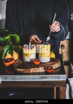 Frau, die Müsli mit Mango-Smoothie und Müsli mit Löffel isst Stockfoto