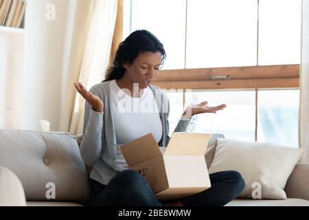 Enttäuschtes schwarzes junges Mädchen öffnet einen Karton Stockfoto