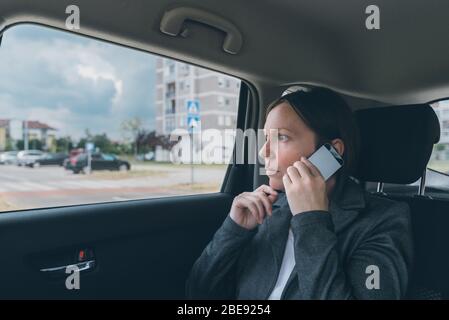 Zweifelnd Geschäftsfrau Gespräch am Handy auf dem Rücksitz, Wirtschaft in Bewegung Konzept. Elegante nach kaukasischen weibliche Person mit Smartphone Stockfoto