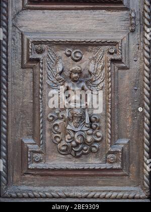 Detail eines Engels, der auf dem Holzportal einer alten italienischen Kirche geschnitzt ist. Stockfoto