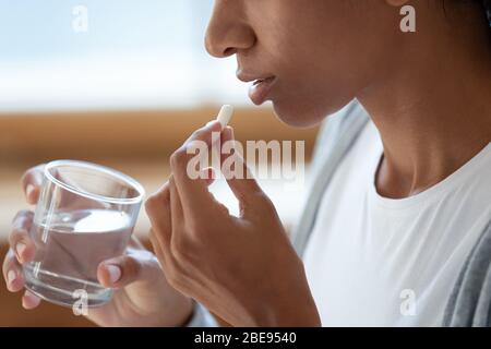 Schwarzes Mädchen halten Glas Wasser und Pillen in der Nähe Gesicht Stockfoto