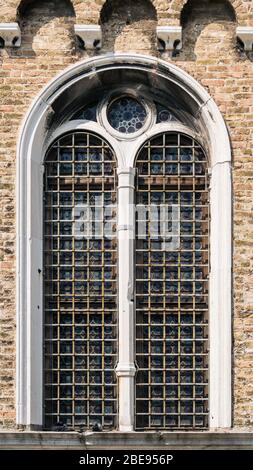 Die Verschließung des mehrbeinigen Fensters in weißem Stein auf der Ziegelwand. Stockfoto