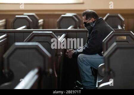 Eine einsames Person, die eine schützende Gesichtsmaske trägt, betet in der katholischen Kirche des Heiligsten Erlösers am Ostersonntag in Boston Massachusetts USA Stockfoto