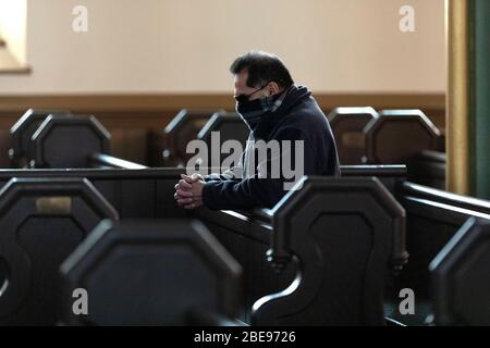 Eine einsames Person, die eine schützende Gesichtsmaske trägt, betet in der katholischen Kirche des Heiligsten Erlösers am Ostersonntag in Boston Massachusetts USA Stockfoto