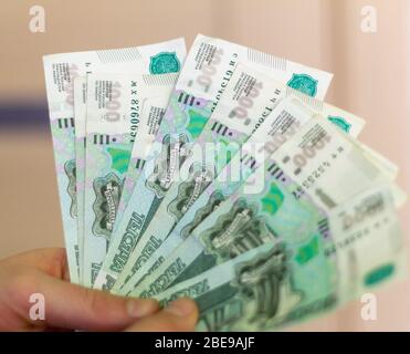 Russian Money.EIN junger Mann hält Banknoten mit einem Nennwert von 1000 Rubel. VIEL Geld in der Hand, Nahaufnahme. Stockfoto