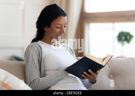 Junge lächelnde afroamerikanische Mädchen lesen Buch Stockfoto