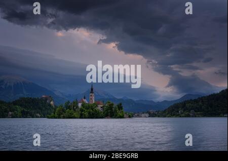 Der Sonnenaufgang über dem Bleder See, der Insel, der Kirche und der Burg mit den Bergkette Stol, Vrtaca, Begunjscica im Hintergrund - Bled, Slowenien Stockfoto
