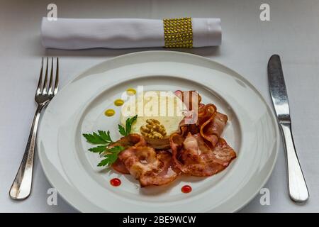 Warmer Ziegenkäse mit Honig und Speck auf einem weißen Gericht. Stockfoto