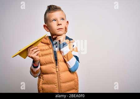 Junge kleine kaukasische Kind mit Spaß und spielen Phantasie fliegen mit Papier Flugzeug ernstes Gesicht denken über Frage, sehr verwirrt Idee Stockfoto
