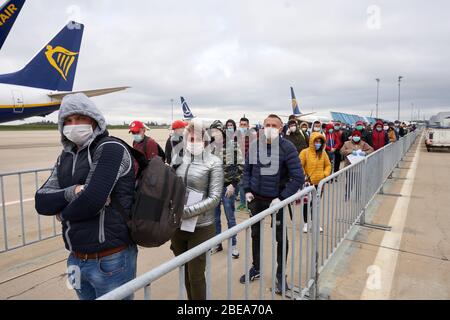 Hahn, Deutschland. April 2020. Hahn, Deutschland. April 2020. Nach der Landung am Flughafen Hahn stehen rund 160 rumänische Erntearbeiter in einer langen Schlange vor der Gesundheits- und Sicherheitskontrolle auf dem Vorfeld. Wegen der Coronavirus-Pandemie war lange unklar, ob Arbeitnehmer aus Osteuropa rechtzeitig in das Land einreisen dürfen. Bild: Thomas Frey/dpa/Alamy Live News Bild: dpa picture Alliance/Alamy Live News Stockfoto