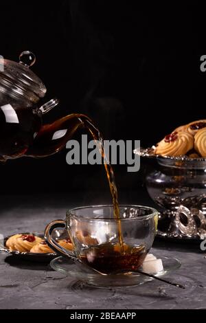 Heißer Tee aus der Teekanne wird in eine Tasse gegossen Stockfoto