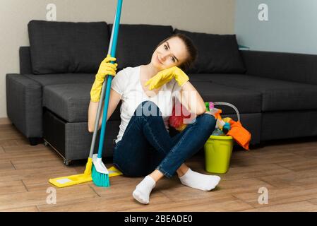 Ein Mädchen hält Waschmittel in einem Eimer auf dem Hintergrund. Frau ist bereit, Haus zu reinigen. Eine Hausfrau ist Hausfrau. Stockfoto