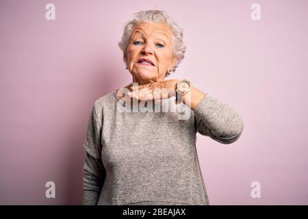 Senior schöne Frau mit lässigen T-Shirt über isoliert rosa Hintergrund Schneiden Kehle mit der Hand als Messer stehen, bedrohen Aggression mit furio Stockfoto