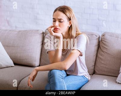 Selbstisolierung. Nachdenkliches Mädchen sitzt auf dem Sofa Stockfoto