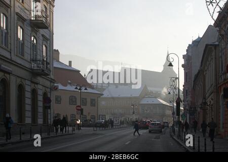 Strada Muresenilor, Straße in der Altstadt von Brasov, Rumänien, im Winter. Die schwarze Kirche Silhouette im Hintergrund. Stockfoto