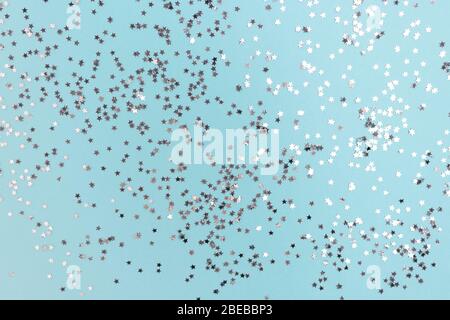 Textur aus glänzenden silbernen Sternen auf blauem Pastellgrund. Urlaubskulisse. Stockfoto