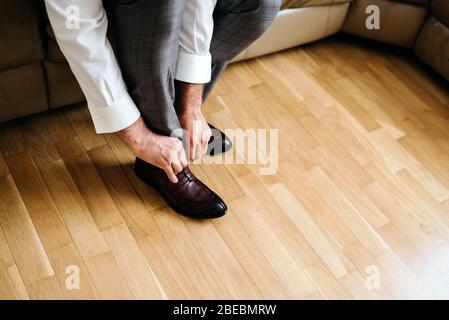 Geschäftsmann, der Schuhe anzieht, Mann, der sich für die Arbeit vorbereitet, Bräutigam Morgen vor der Hochzeitszeremonie Stockfoto