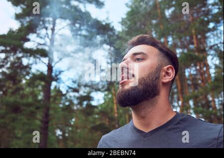 Porträt eines jungen, bärtigen Mannes, auf, vor einem Hintergrund der Tierwelt. Das Konzept von Expedition, Abenteuer und Camping-Leben. Stockfoto