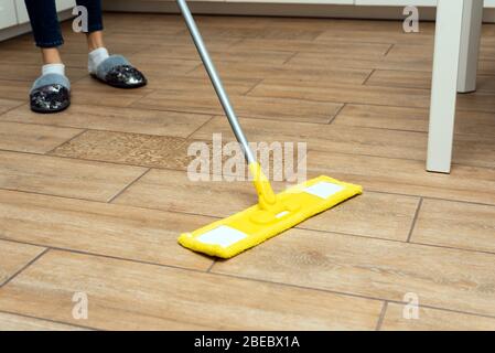 Eine Frau wäscht in ihrem Haus Fußbodenheizung. Ein Mopp in den Händen einer Haushälterin. Stockfoto