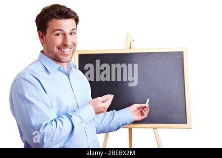 Ein lachender Lehrer steht in Kreide vor einer Tafel Stockfoto