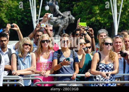 Junge und attraktive Touristen, die eine Veranstaltung vor dem Buckingham Palace London England Großbritannien fotografieren Stockfoto