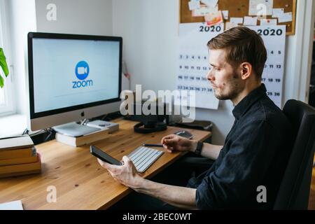 Riga, Lettland - März 28 2020: Junger Mann mit Zoom Videokonferenz-Anruf über Computer. Heimbüro. Bleiben Sie zu Hause und arbeiten von zu Hause Konzept während Stockfoto