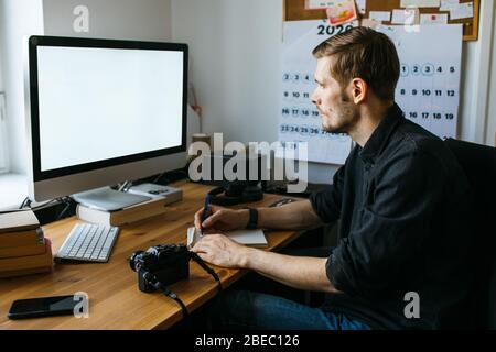 Mann, der vom Heimbüro aus arbeitet. Computer mit leerem leeren Bildschirm für Kopierspeicher und Informationen. Geschäftsmann aus der Hinteransicht. Online-Kurse Stockfoto