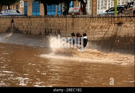 Sanaa, Jemen. April 2020. Nach starkem Regen fahren Menschen in Sanaa, Jemen, 13. April 2020, mit dem Motorrad durch eine überflutete Straße. Am Montag traf Sanaa ein heftiger Regen. Kredit: Mohammed Mohammed/Xinhua/Alamy Live News Stockfoto