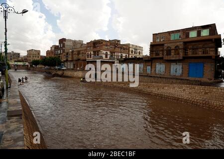 Sanaa, Jemen. April 2020. Nach starkem Regen versuchen die Menschen, eine überflutete Straße in Sanaa, Jemen, am 13. April 2020 zu überqueren. Am Montag traf Sanaa ein heftiger Regen. Kredit: Mohammed Mohammed/Xinhua/Alamy Live News Stockfoto