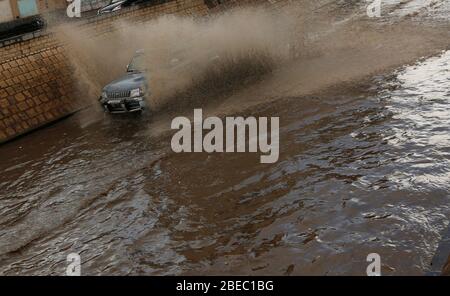 Sanaa, Jemen. April 2020. Nach starkem Regen fährt ein Auto durch eine überflutete Straße in Sanaa, Jemen, 13. April 2020. Am Montag traf Sanaa ein heftiger Regen. Kredit: Mohammed Mohammed/Xinhua/Alamy Live News Stockfoto