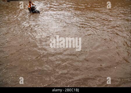 Sanaa, Jemen. April 2020. Ein Mann fährt nach starkem Regen in Sanaa, Jemen, 13. April 2020, mit dem Motorrad durch eine überflutete Straße. Am Montag traf Sanaa ein heftiger Regen. Kredit: Mohammed Mohammed/Xinhua/Alamy Live News Stockfoto