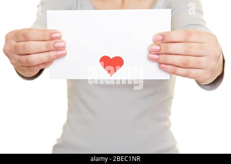 Weibliche Hände halten einen Liebesbrief mit einem roten Herzen Stockfoto