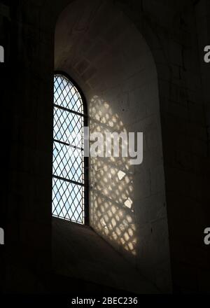 Details von Licht, Fenstern, Mauerwerk und Schatten innerhalb einer klassischen europäischen Kirche. Stockfoto