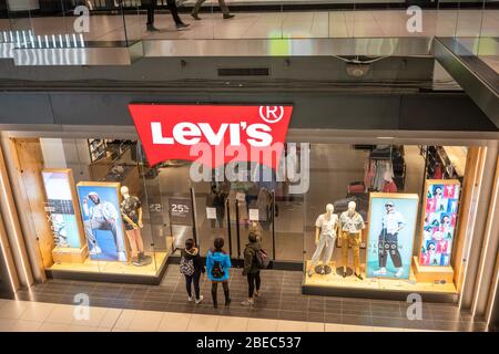 Die Leute lasen ein Schild auf dem Levi's Laden, das besagt, dass es geschlossen ist, im Eaton Centre Mall in der Innenstadt von Toronto, Kanada, 17. März 2020. Inmitten von Sicherheitsmaßnahmen, die darauf ausgerichtet sind, die Ausbreitung des COVID-19-Virus zu verlangsamen, erklärte die Provinz Ontario am 17. März 2020 den Ausnahmezustand. Die neuen Vorschriften werden die Menschen, die in Restaurants gehen, weitgehend einschränken und unter anderem Bars, Fitnessstudios, Kirchen schließen. Stockfoto