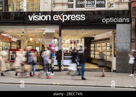 LONDON - MAI 2019: Vision Express Store auf der Oxford Street mit Menschen in Bewegung verschwimmen - ein großer britischer High-Street-Optiker Stockfoto