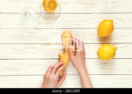 Ingwer-Zitrone in den Händen auf weißem Holzhintergrund, Vorbeugung von Erkältungen. Selektiver Fokus. Stockfoto