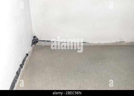 Bodenausdehnungsband am Boden der Wand auf dem neu gemachten Boden im Haus, um ein Rissen des Bodens zu verhindern. Stockfoto