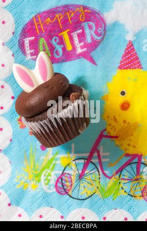 M&S Easter Cupcake auf Serviette Serviette Serviette - Mini-Schokolade Cupcakes mit Schokolade Buttercreme und Ostern Dekorationen - Osterhasen Ohren Stockfoto
